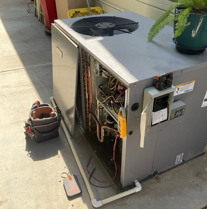 Technician repairing an air conditioner unit in New Delhi workshop.
